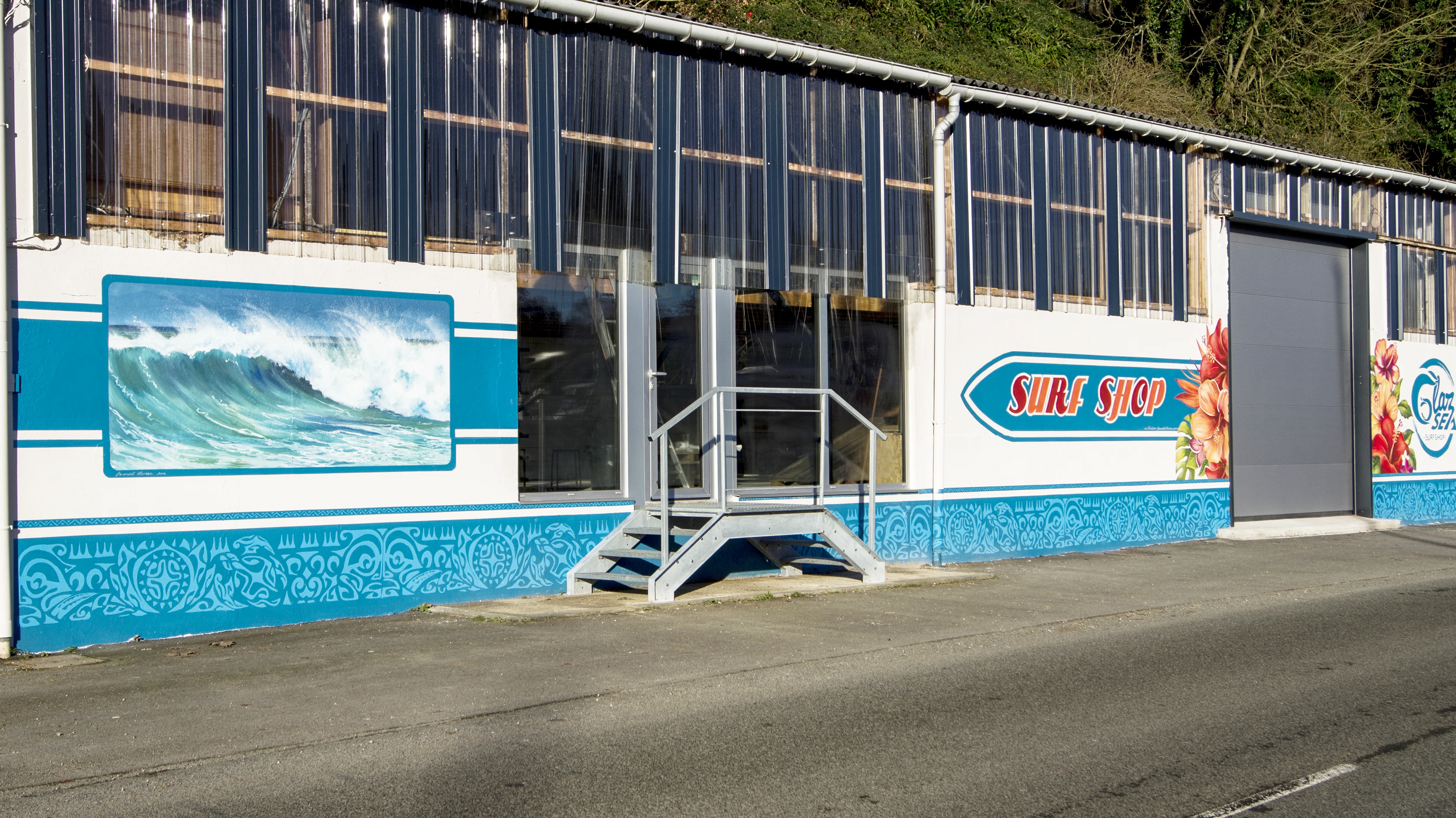 Façade du surf shop Glaz Sea avec sa grande vague peinte et sa décoration polynésienne sur les bas de mur